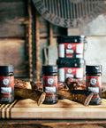 Brock Lesnar Bearded Butcher Blend Seasoning Shakers and Buckets in front of Tomahawk Steak