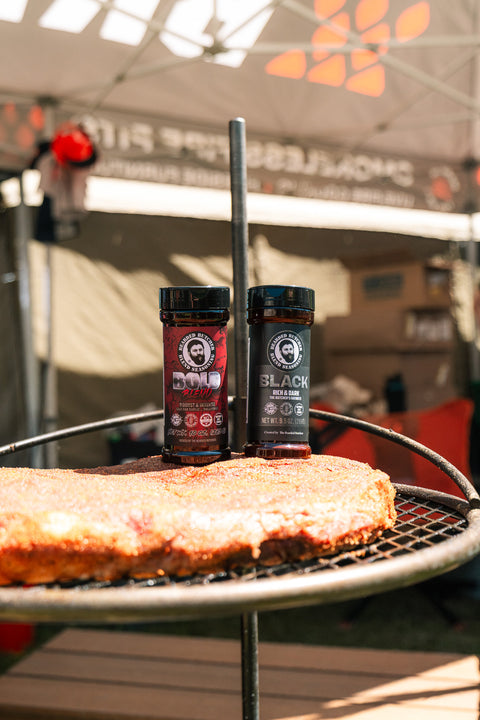 Two bottles of spice on a grill with a blurred background