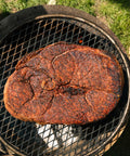 Rust-covered steak on a grill with grass in the background