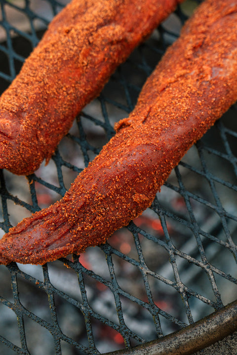 Two tenderloins with a spice rub on a grill grate.