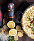 Dish of hot cheese dip with jalapeños and bacon, accompanied by hot sauce and lemon slices on a wooden surface.