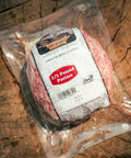 Packaged ground beef patties with a label on a wooden surface