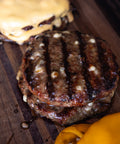 Grilled hamburger patties on a wooden cutting board with a blurred background