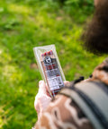 Person holding a package of beef sticks outdoors with green grass in the background
