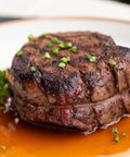 Grilled steak with a red sauce on a white plate