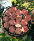Raw burgers on a grill with a grassy background