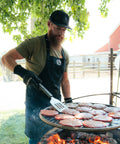 Man grilling hamburgers outdoors with a scenic background