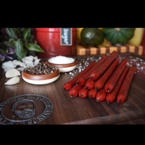 Beef sticks stacked on cutting board with spices 